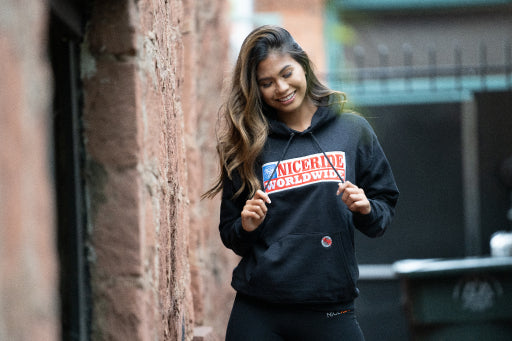 Young woman showcasing NICERIDE hoodie, embodying trendy fall fashion style with a playful smile.