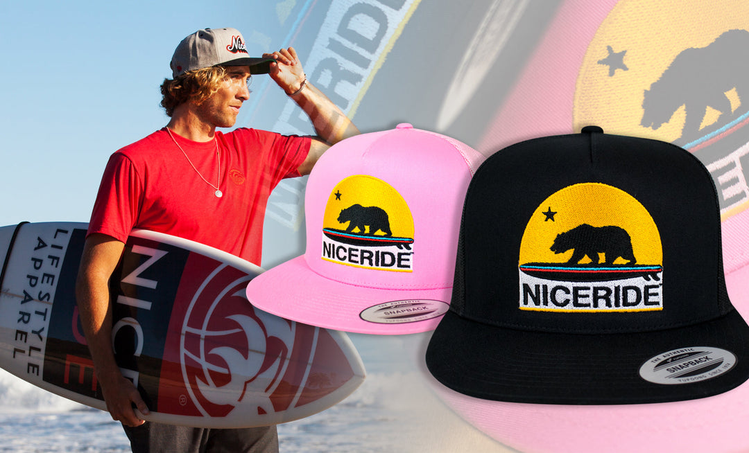 Surfer wearing a red shirt with hats featuring the bear emblem, representing the american lifestyle and apparel culture.