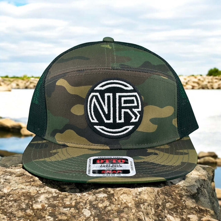 Inner Circle Unisex 7 Panel Trucker Hat featuring NR logo in camo design on rocky surface