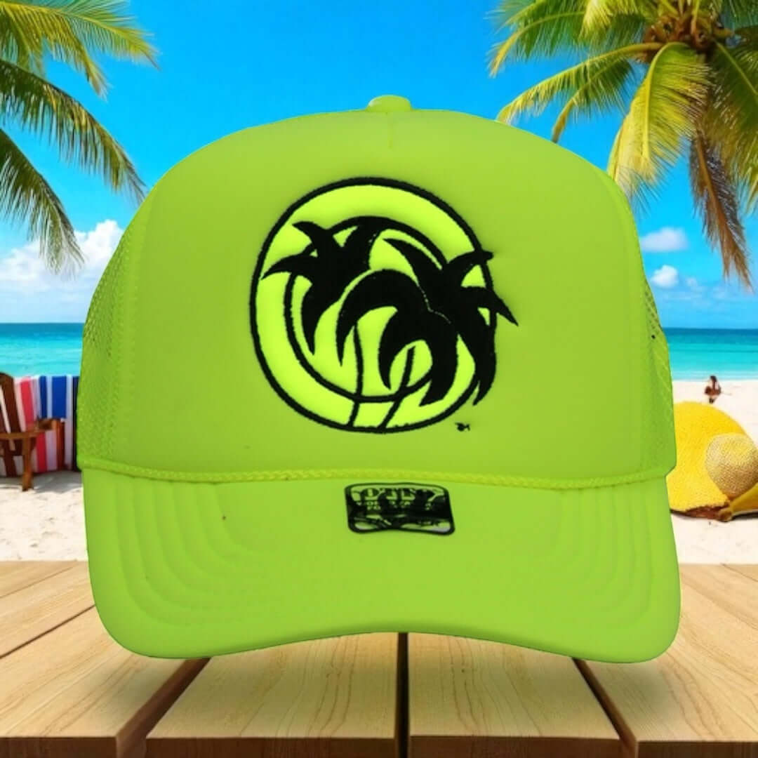 Bright yellow unisex foam trucker hat with palm tree logo, set against a beach background.
