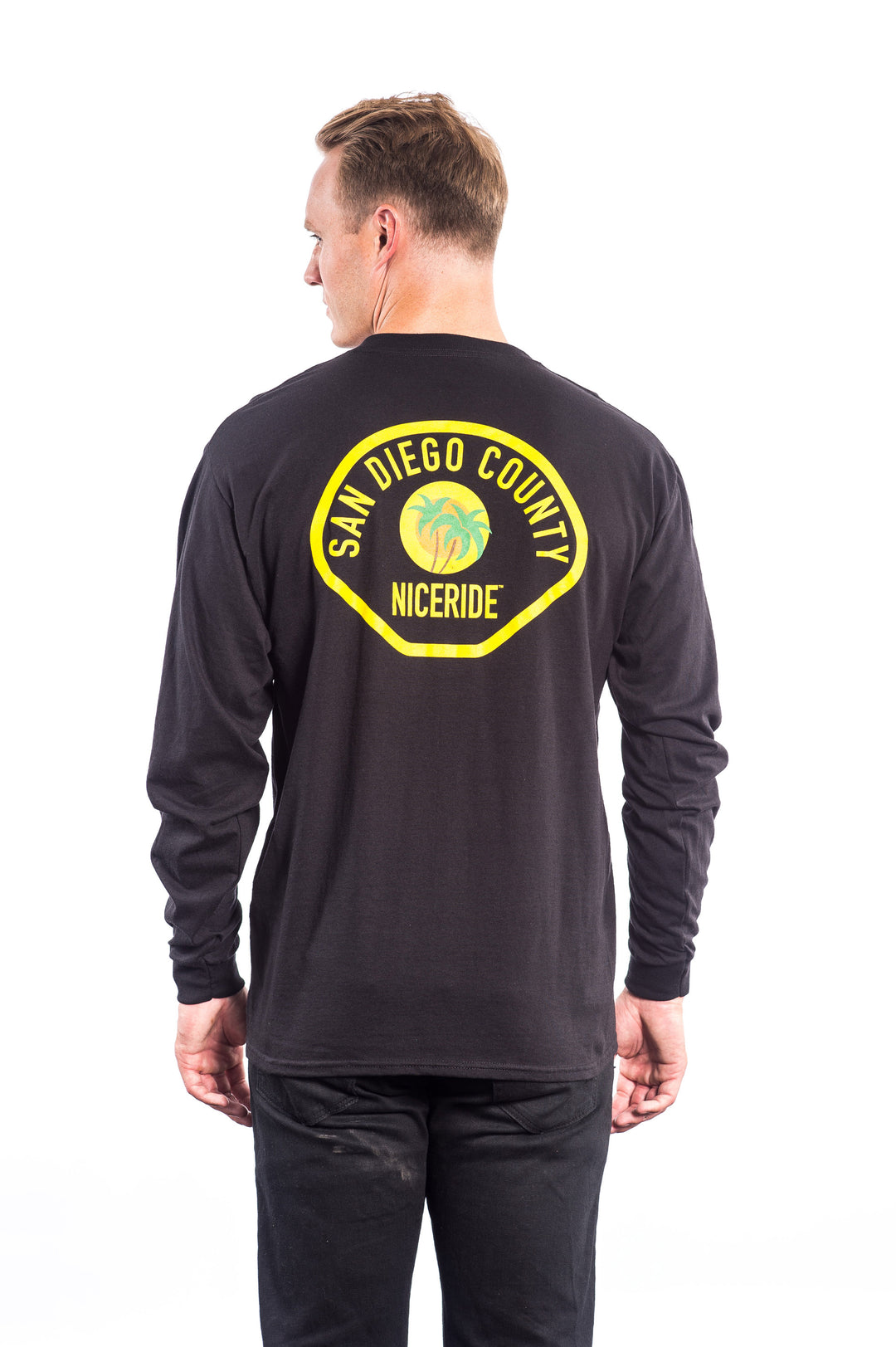Model wearing The Badge Hanes pre-shrunk 100% cotton long sleeve shirt featuring San Diego County NICERIDE design.