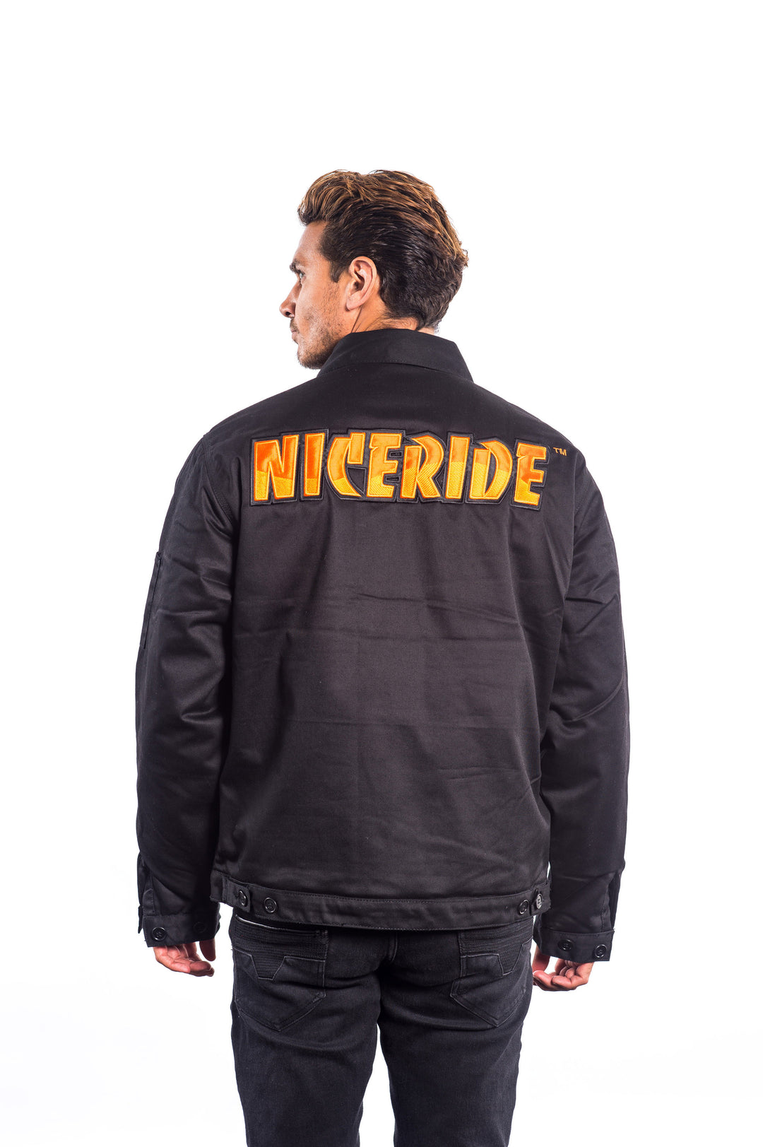 Man wearing a black canvas jacket with NICERIDE embroidered on the back and left chest.