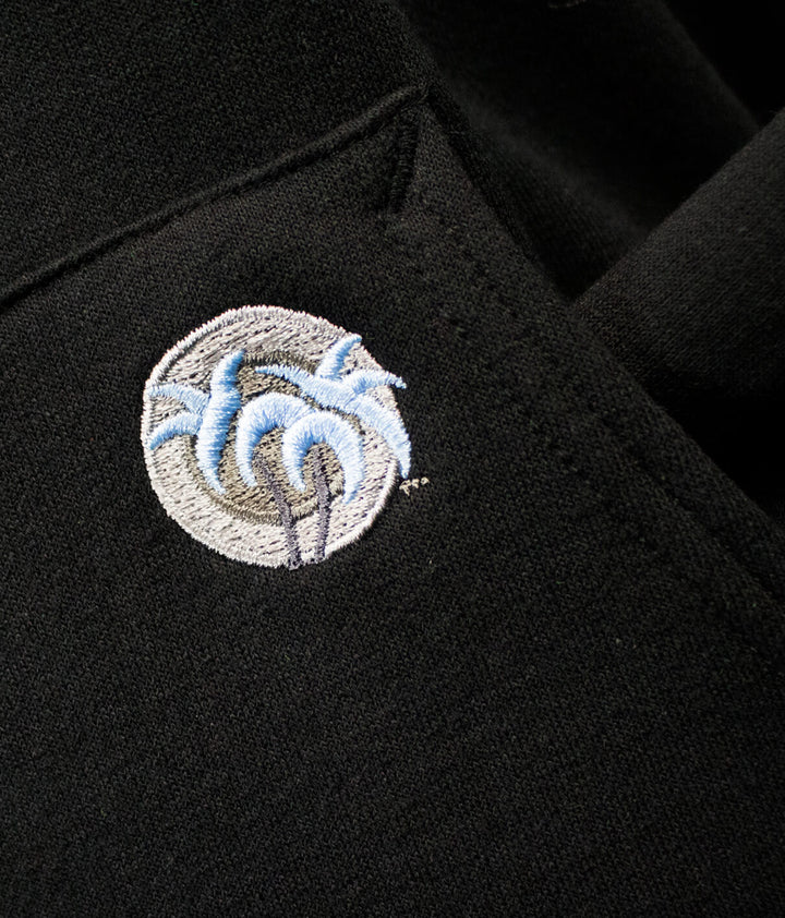 Close-up of NICERIDE palm logo embroidered on black pullover hoodie, showcasing quality craftsmanship.