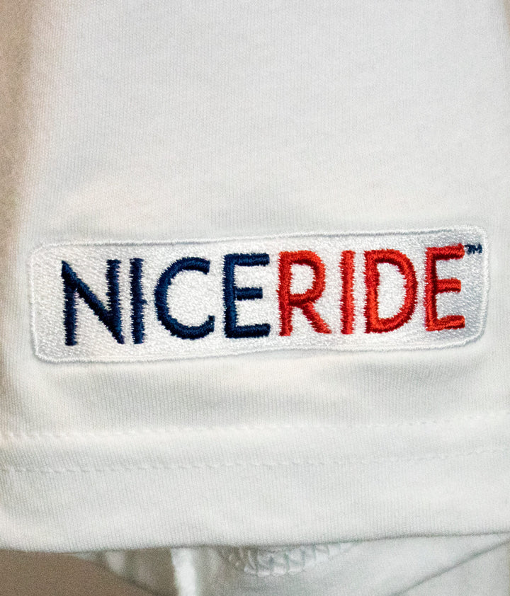 Close-up of NICERIDE logo embroidered on the sleeve of a t-shirt.