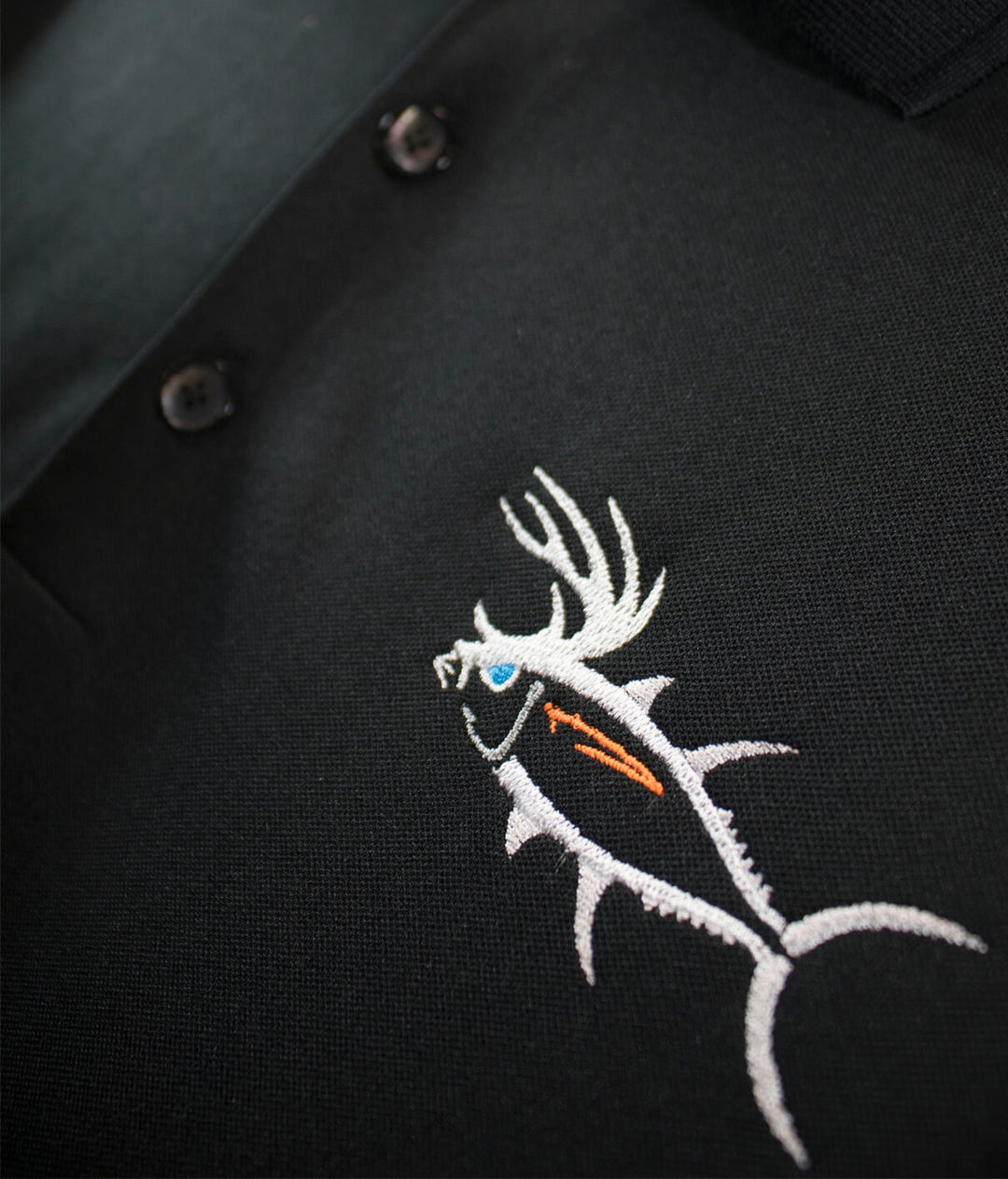 Embroidered fish design on black polo shirt, showcasing quality craftsmanship and attention to detail.