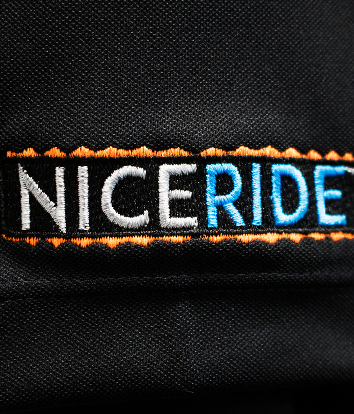 Embroidery of NICERIDE logo on black fabric of Buck-Eye Nike golf shirt.