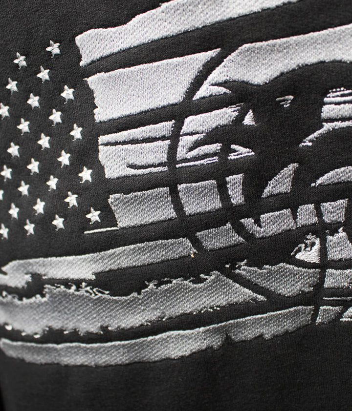 Close-up of the American flag design on the Strong Faded hoodie, featuring black and silver embroidery details.
