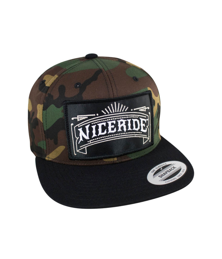 Cholo patch camo snapback hat featuring NICERIDE logo on the front and camouflage pattern.