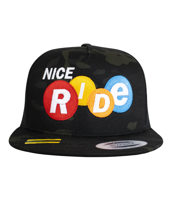Front view of the "Nikki" Trucker Hat featuring NICERIDE logo embroidered on black camouflage fabric.
