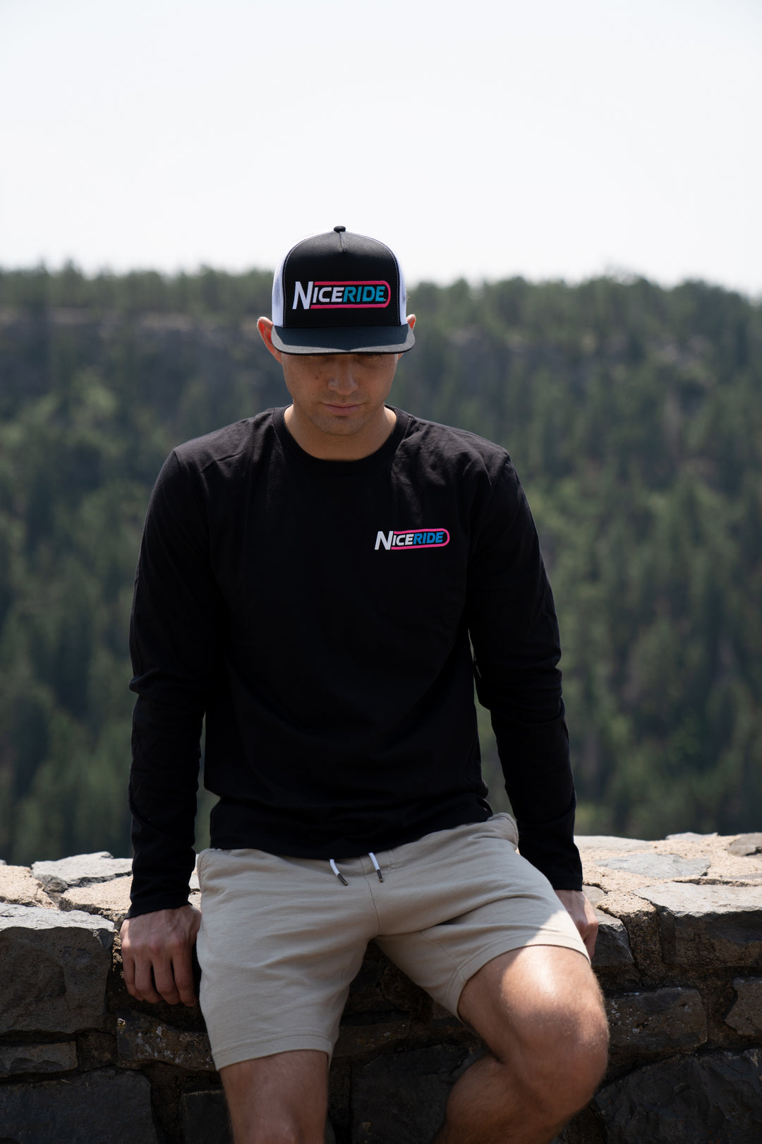 Man wearing NICERIDE Trucker Hat and black long sleeve shirt outdoors with a forest background.