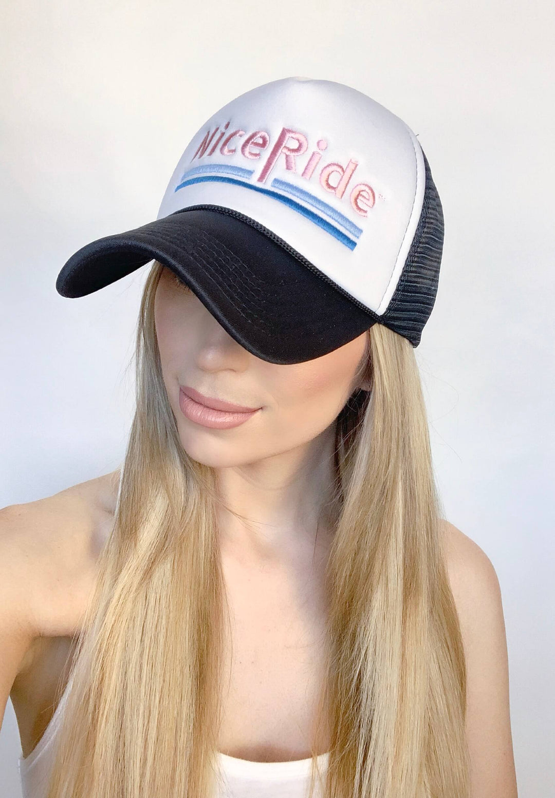 Female model wearing a foam trucker hat with "Nice Ride" embroidered on the front.
