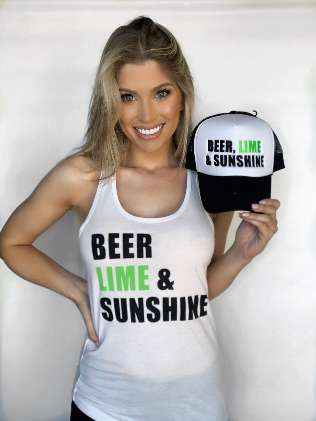 Woman wearing Beer, Lime &amp; Sunshine tank top holding matching cap featuring the same design, perfect for casual outings.