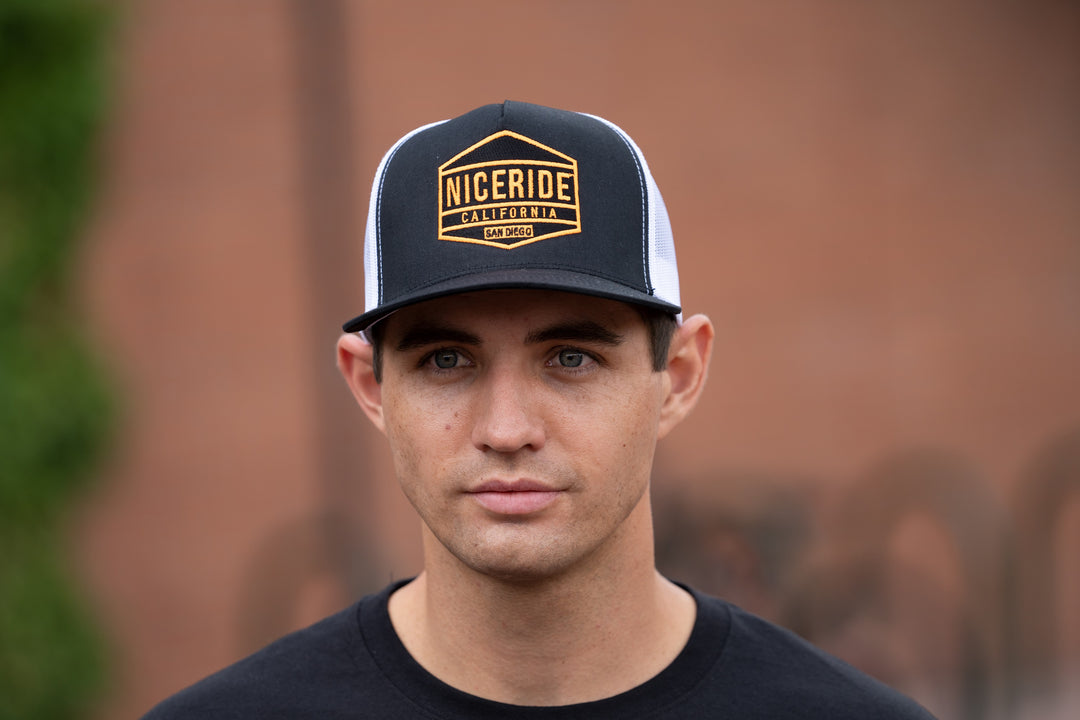 Man wearing a black and white Good Times hat from NICERIDE with a logo on the front.